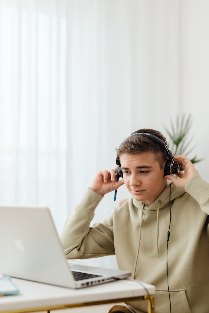 The Art of Drawing Readers In: Your attractive post title goes here Teenage boy using headphones and laptop for online learning at home.